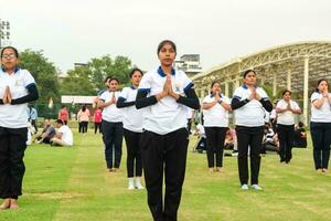 New Delhi, India, June 21, 2023 - Group Yoga exercise session for people at Yamuna Sports Complex in Delhi on International Yoga Day, Big group of adults attending yoga class in cricket stadium photo