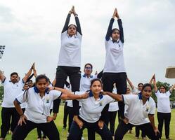 New Delhi, India, June 21, 2023 - Group Yoga exercise session for people at Yamuna Sports Complex in Delhi on International Yoga Day, Big group of adults attending yoga class in cricket stadium photo