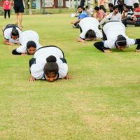 nuevo Delhi, India, junio 21, 2023 - grupo yoga ejercicio sesión para personas a yamuna Deportes complejo en Delhi en internacional yoga día, grande grupo de adultos asistiendo yoga clase en Grillo estadio foto