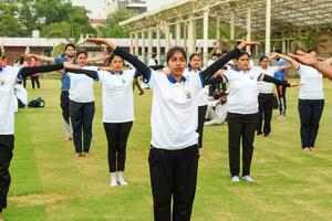 New Delhi, India, June 21, 2023 - Group Yoga exercise session for people at Yamuna Sports Complex in Delhi on International Yoga Day, Big group of adults attending yoga class in cricket stadium photo