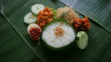 Savory rice, noodles, cucumber, and seasoned potatoes on a banana leaf. Indonesian traditional food for independence day celebration photo