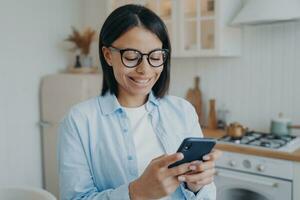 Smiling woman use mobile phone apps, order groceries in online store, check social networks at home photo