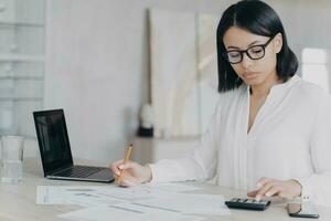 Remote accountant is calculating profit. Young hispanic bookkeeper is working distantly from home. photo