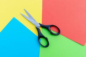 Scissors placed on colored papers, after some edits. photo