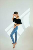 Beautiful slim young caucaisn woman in black blose and jeans on white background in photo studio