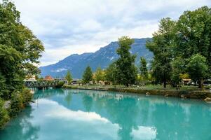 A beautiful emerald green river that is so clear that it reflects the sky and scenery. In Interlaken, Switzerland, the Aare River with natural water sources flowing down from high mountains. photo