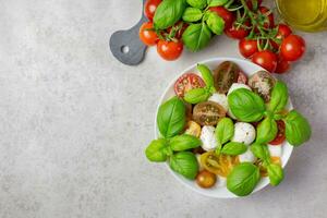 Traditional italian caprese salad with cherry tomatoes, mozzarella, basil, olive oil, spices and sea salt. Organic and natural food concept. Light background. Top view. Copy space. photo