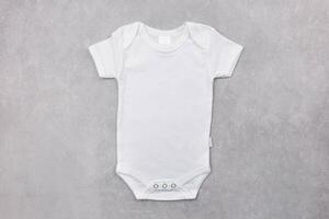 White baby girl or boy bodysuit mockup flat lay on the gray concrete background. Design onesie template, print presentation mock up. Top view. photo