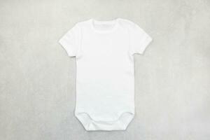 White baby girl or boy bodysuit mockup flat lay on the gray concrete background. Design onesie template, print presentation mock up. Top view. photo