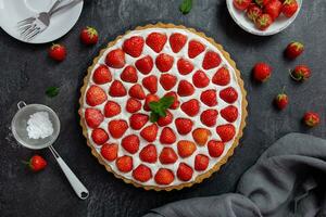 Delicious strawberry tart with whipped cream and mascarpone on a dark concrete background. Top view. photo