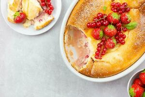 Homemade casserole with cottage cheese, semolina, fresh red currant berries and strawberry on light gray background. Top view. Copy space. Close up. photo