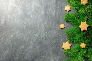 Christmas traditional gingerbread stars cookies with christmas tree branches on a dark stone background. Top view. Copy space. photo