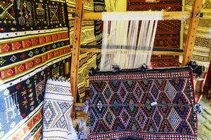 A traditional rug being woven on a carpet vertical loom, showing wool pile under tension, foundation, warp and weft. photo