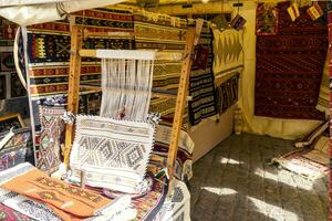 A traditional rug being woven on a carpet vertical loom, showing wool pile under tension, foundation, warp and weft. photo