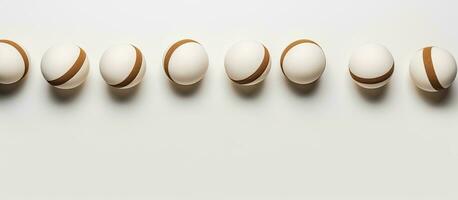 Photo of a row of white and brown balls on a white surface with plenty of copy space with copy space