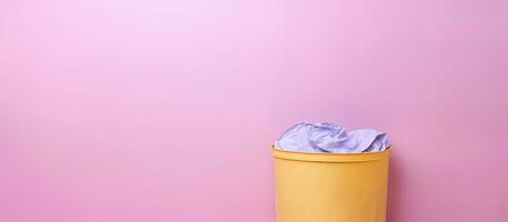 Photo of a yellow trash can on a pink wall with copy space with copy space