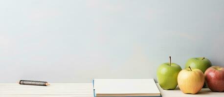 Photo of a table with a book, pencil, and apples with copy space