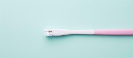 Photo of a pink and white toothbrush on a blue background with copy space with copy space