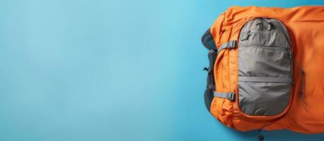 Photo of an orange backpack hanging on a blue wall with plenty of space for your own creative message with copy space