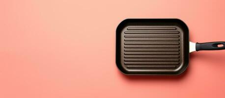 Photo of a grilling pan with a spatula on a vibrant pink background with copy space