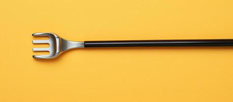 Photo of a black handled fork on a vibrant yellow background with plenty of space for text or other elements with copy space