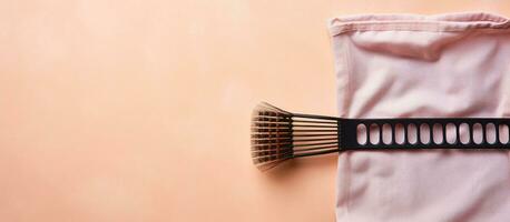 Photo of a pink towel and a black brush on a table with copy space with copy space