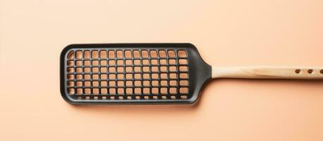 Photo of a frying pan with a wooden handle on a pink background, with copy space with copy space