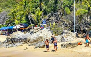 Puerto Escondido Oaxaca Mexico 2023 Palms parasols sun loungers beach people Zicatela Puerto Escondido Mexico. photo