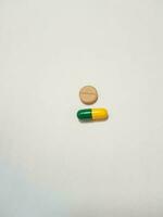 isolated white photo of a brown tablet and a green and yellow capsule