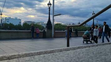 hermosa bajo ángulo imágenes de turista personas son caminando a lo largo ruta de Londres ojo a Westminster central Londres ciudad de Inglaterra genial Bretaña, imágenes estaba capturado en ago 02, 2023 durante puesta de sol. video