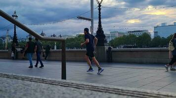 hermosa bajo ángulo imágenes de turista personas son caminando a lo largo ruta de Londres ojo a Westminster central Londres ciudad de Inglaterra genial Bretaña, imágenes estaba capturado en ago 02, 2023 durante puesta de sol. video