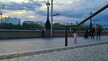 hermosa bajo ángulo imágenes de turista personas son caminando a lo largo ruta de Londres ojo a Westminster central Londres ciudad de Inglaterra genial Bretaña, imágenes estaba capturado en ago 02, 2023 durante puesta de sol. video