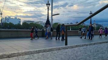 hermosa bajo ángulo imágenes de turista personas son caminando a lo largo ruta de Londres ojo a Westminster central Londres ciudad de Inglaterra genial Bretaña, imágenes estaba capturado en ago 02, 2023 durante puesta de sol. video