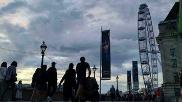 hermosa bajo ángulo imágenes de turista personas son caminando a lo largo ruta de Londres ojo a Westminster central Londres ciudad de Inglaterra genial Bretaña, imágenes estaba capturado en ago 02, 2023 durante puesta de sol. video