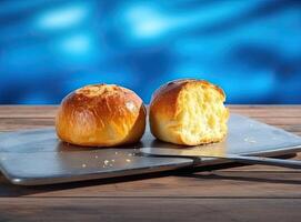Foil wrapped processed cream cheese, table knife and slice of bread on a cutting board over blue wooden table. Small triangular pieces of soft cheese. Created with Generative AI technology. photo