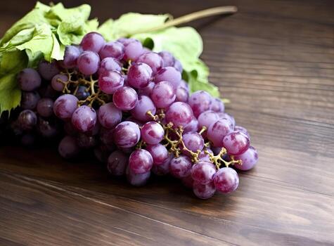 Bunches of fresh ripe red grapes on a wooden textural surface. Ancient style, a beautiful background with a branch of black grape. Red grapes in a box on a stone table, purple grapes, side viwe. photo