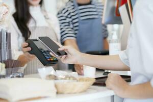 Female customer holding phone near nfc terminal make contactless mobile payment. photo