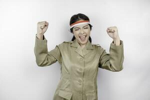 A young Asian government worker with a happy successful expression, wearing flag headband and khaki uniform isolated by white background. Indonesia's independence day concept. photo