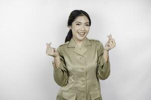 un joven asiático mujer en marrón caqui uniforme demostración oferta sensación por formación corazón con su dedos. indonesio gobierno obrero. foto