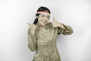 Smiling government worker woman gesturing OK sign with her thumbs up isolated by white background. PNS wearing khaki uniform. Indonesia's independence day concept. photo