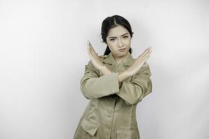 Young Asian woman wearing a brown uniform shows crossed hands or stop gesture, isolated white background photo