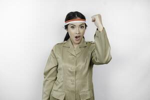 A young Asian government worker with a happy successful expression, wearing flag headband and khaki uniform isolated by white background. Indonesia's independence day concept. photo