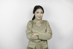 A young Asian woman in brown khaki uniform showing confident gesture by folding her arms. Indonesian government worker. photo