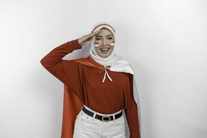 indonesio musulmán mujer vistiendo hijab dar saludo con orgulloso gesto mientras participación de indonesia bandera. de indonesia independencia día concepto foto