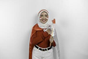 indonesio musulmán mujer vistiendo hijab dar saludo con orgulloso gesto mientras participación de indonesia bandera. de indonesia independencia día concepto foto