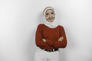A confident Indonesian muslim woman folding her arms and wearing red top and white hijab to celebrate Indonesia Independence Day. Isolated by white background. photo