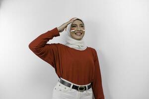 Beautiful Asian woman wearing red top and white hijab giving salute celebrate Indonesian independence day on August 17 isolated over white background photo