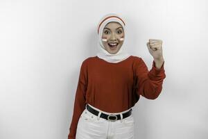 A young Asian muslim woman with a happy successful expression wearing red top and white hijab isolated by white background. Indonesia's independence day concept. photo