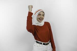 A young Asian muslim woman with a happy successful expression wearing red top and white hijab isolated by white background. Indonesia's independence day concept. photo