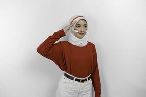 Beautiful Asian woman wearing red top and white hijab giving salute celebrate Indonesian independence day on August 17 isolated over white background photo